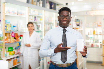 African american male who came to the pharmacy chooses capsules for rubbing, restoring hair...