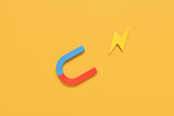 Horseshoe shaped magnet with paper lightning on yellow background