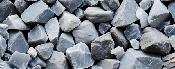 Closeup of angular riverbed stones These stones have sharp, angular edges that give them a faceted appearance. They are mostly grey in color and have a rough texture.