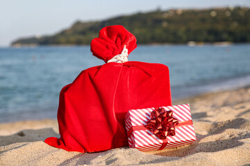 Santa bag and gift box on sea beach. Christmas vacation concept