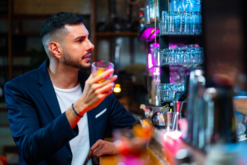 Caucasian man hanging out drinking whiskey on bar counter at luxury nightclub on weekend vacation. Bartender making mixed alcoholic cocktail drink for customer celebrating holiday party at restaurant.