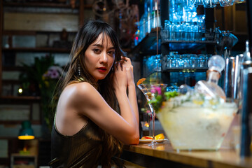 Portrait of Attractive Asian woman relax and enjoy hangout nightlife and drinking fancy cocktail at luxury restaurant bar. Beautiful female celebrating holiday event party at nightclub in the city