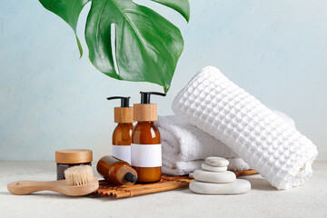 Composition with different cosmetic products, spa accessories and palm leaf on light background