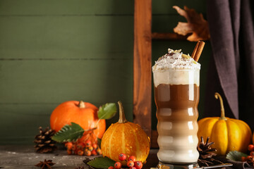 Glass of tasty pumpkin latte with cinnamon and almond on grey table