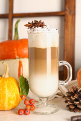 Glass cup of tasty pumpkin latte with star anise and viburnum on white table