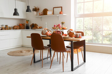Interior of modern kitchen with served dining table and pumpkins
