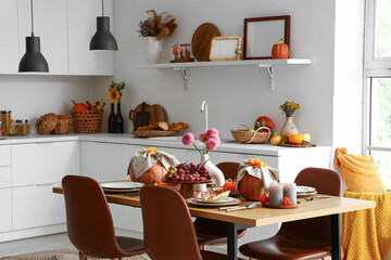Interior of modern kitchen with served dining table and pumpkins