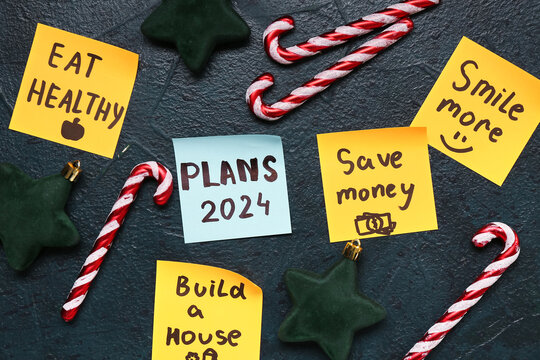 Sticky notes with different goals for 2024 and Christmas decorations on grunge black background