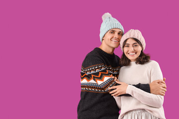 Happy young couple in warm clothes on purple background