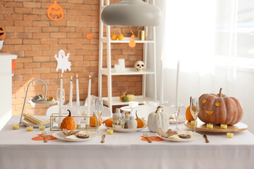 Beautiful table setting with pumpkins and burning candles for Halloween party at home