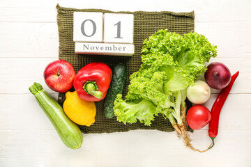 Fresh vegetables, fruits and cube calendar with date NOVEMBER 1 on white wooden background. World...