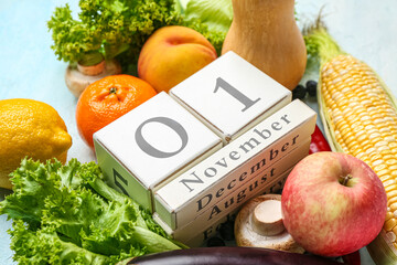 Fresh vegetables, fruits and cube calendar with date NOVEMBER 1 on blue background. World Vegan Day...