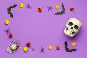 Frame made of skulls, paper bats and marigold flowers for Halloween celebration on purple background