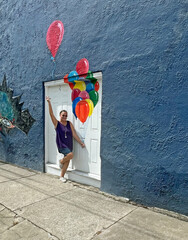 senior adult woman holding balloons on wall painting