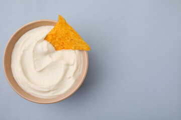 Delicious tofu sauce served with nachos chip in bowl on grey background, top view. Space for text