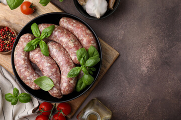 Raw homemade sausages and different products on grey table, flat lay. Space for text
