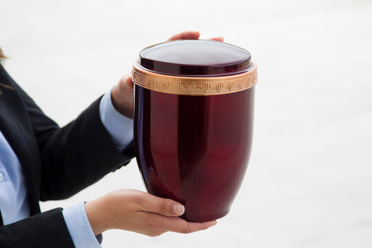 Funerary urn held by two hands on white background