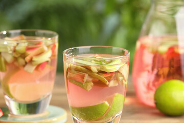 Fototapeta premium Tasty rhubarb cocktail with lime on table outdoors, closeup