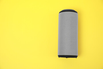 One portable bluetooth speaker on yellow background, top view with space for text. Audio equipment