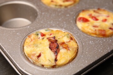 Freshly baked bacon and egg muffins with cheese in tin, closeup