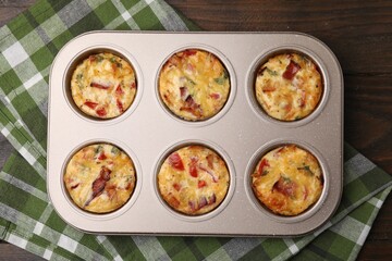 Freshly baked bacon and egg muffins with cheese in tin on table, top view