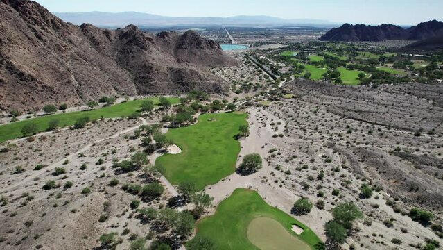 Aerial of golf course nestled amongst dramatic desert mountains in La Quinta
