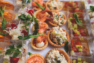 Catering table, beautifully decorated banquet with variety of with different food snacks appetizers on corporate birthday party event or wedding celebration, canape, salad, delicatessen setting