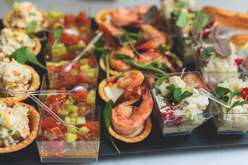 Catering table, beautifully decorated banquet with variety of with different food snacks appetizers on corporate birthday party event or wedding celebration, canape, salad, delicatessen setting