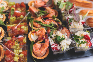 Catering table, beautifully decorated banquet with variety of with different food snacks appetizers on corporate birthday party event or wedding celebration, canape, salad, delicatessen setting