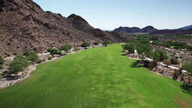 Aerial of golf course nestled amongst dramatic desert mountains in La Quinta