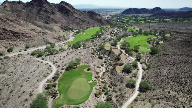 Aerial of golf course nestled amongst dramatic desert mountains in La Quinta