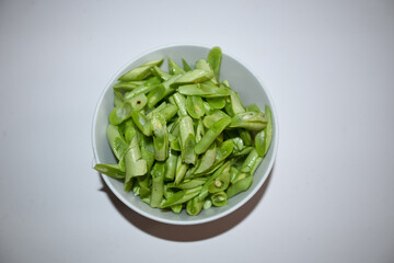 bunch of green beans on a bowl, isolated white background. Buncis or Phaseolus vulgaris  or Phaseolus esculentus.