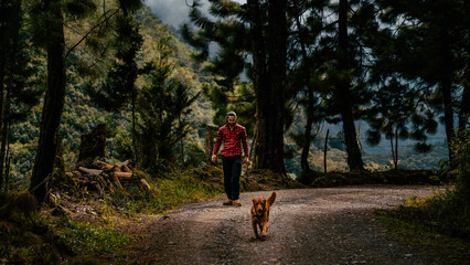 Hombre paseando con su perro en paisaje montañoso - obrazy, fototapety, plakaty