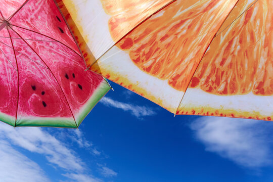 Vibrantly Patterned Orange and Watermelon Beach Umbrellas under the Azure Sky
