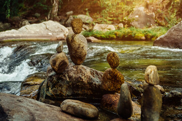 Rocks balance on the bank of stormy mountain river. Balancing stones similar to human figures....