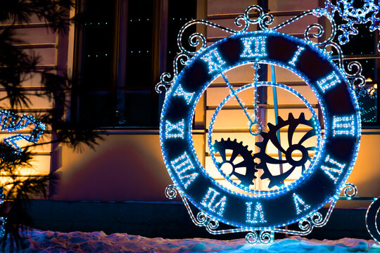 Big clock with Roman numerals on clock face decorated with lights garland outdoors in winter during Christmas holidays with copy space - Powered by Adobe