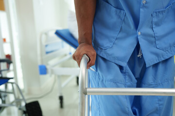 Physical therapist helps a male patient use a walker to practice walking. Support yourself from recovery from sore legs and ankles. Physical therapy service concept.