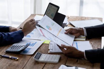 Group of confident business people point to graphs and charts to analyze market data, balance sheet, account, net profit to plan new sales strategies to increase production capacity.	