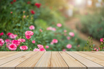 Empty wood table top with blur rose garden background for product display