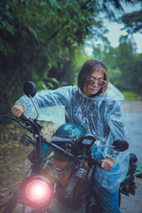 pretty woman wearing plastic rain clothes riding small enduro motorcycle