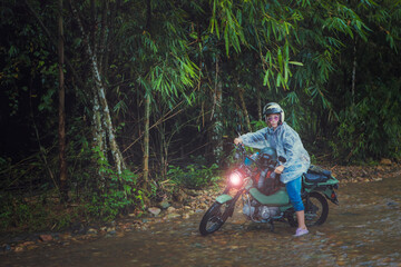 pretty woman riding small enduro motorcycle crossing shallow creek