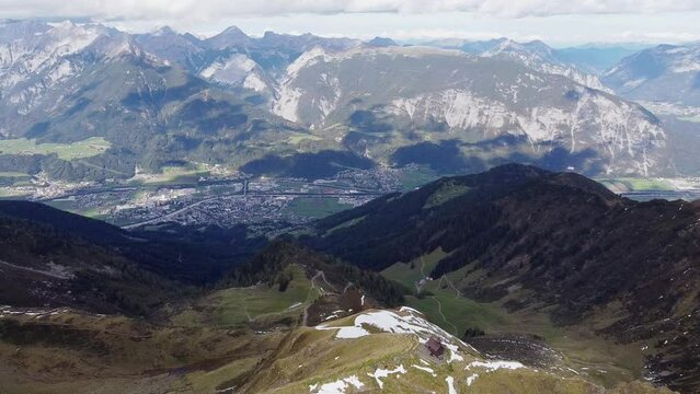 Cinematic aerial of alps mountain top with old wooden chapel on steep peak. Beautiful alpine scenery with valley and town below landscape view. Kellerjoch, Austria. Drone flying around summit, orbit