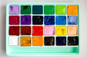 different bright colors of gouache paint in its case