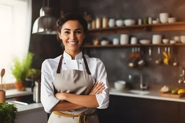 Foto op Canvas Portrait of beautiful female chef in uniform standing on modern kitchen restaurant, crossing arms and looking at camera © AspctStyle