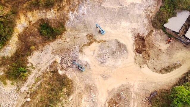 The Mount Pangradinan Mining Industry is located on the edge of Bandung City. Aerial drone footage of dredging and excavation of soil, sand and rock by heavy equipment and transported by trucks. 4K