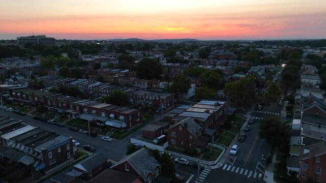 American city during sunset. Aerial rising shot of row houses and homes in urban neighborhood revealing golden sunset in USA.