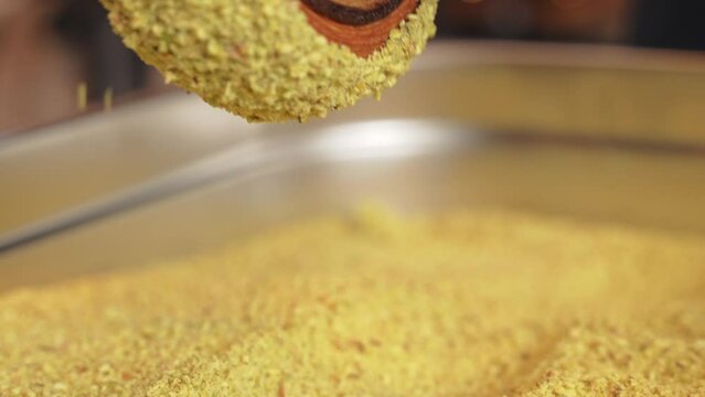 Pistachio croissant donut being decorated rolling over cream and pistachio close up