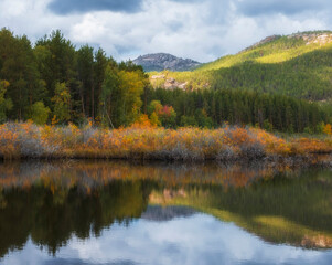 Mountains and forest reflected in the lake in autumn