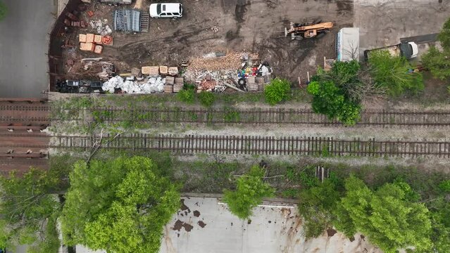 Top down shot of abandoned railroad tracks outside of USA city. Aerial truck shot of overgrown vegetation on useless train tracks.