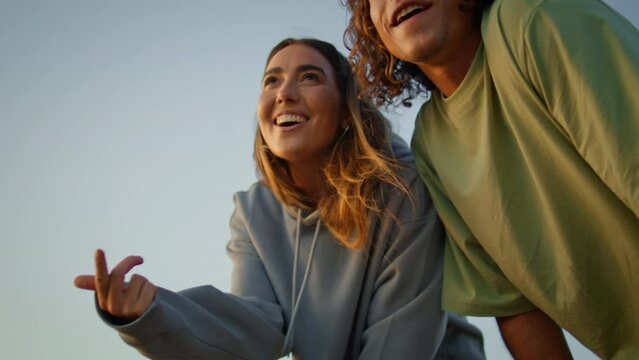 Happy youngsters kissing blue sky background closeup. Young woman throwing rock